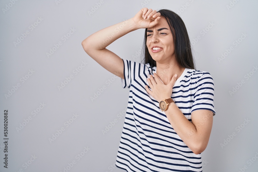 Young brunette woman wearing striped t shirt touching forehead for illness and fever, flu and cold, virus sick Young brunette woman wearing striped t shirt touching forehead for illness and fever, flu and cold, virus sick