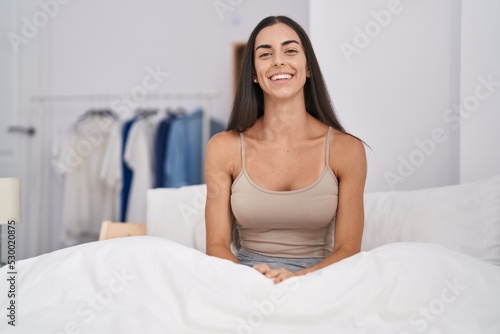 Young brunette woman in the bed at home looking positive and happy standing and smiling with a confident smile showing teeth © Krakenimages.com