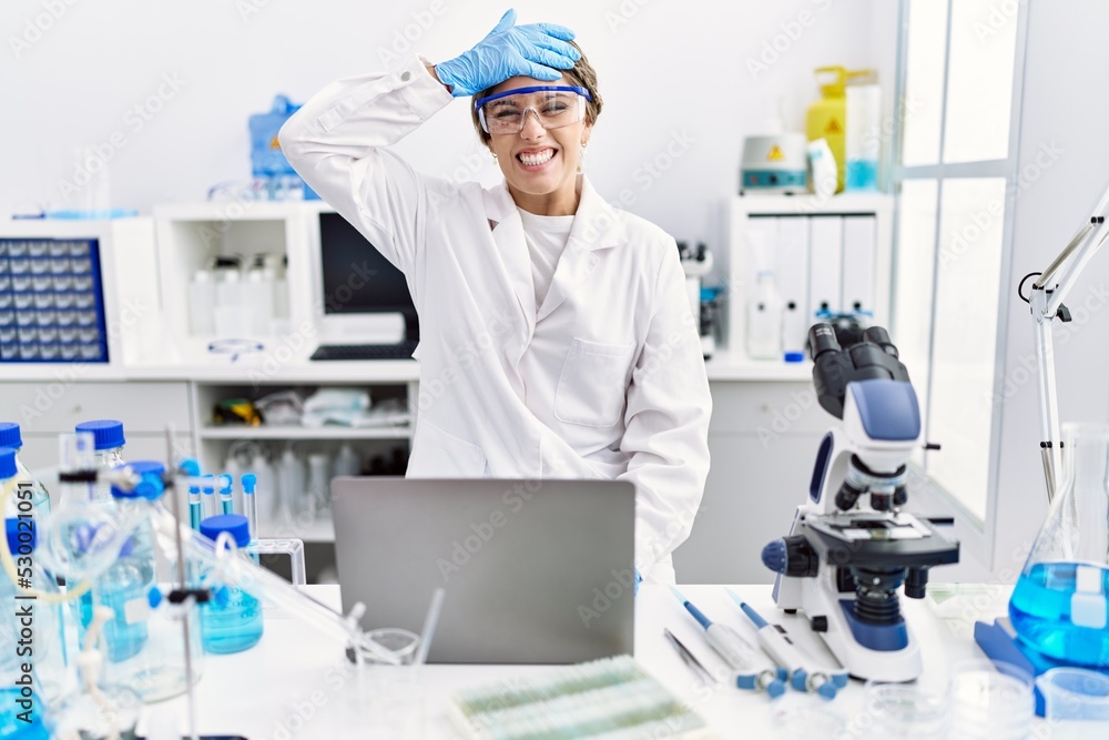 Young hispanic woman wearing scientist uniform working at laboratory stressed and frustrated with hand on head, surprised and angry face Young hispanic woman wearing scientist uniform working at laboratory stressed and frustrated with hand on head, surprised and angry face