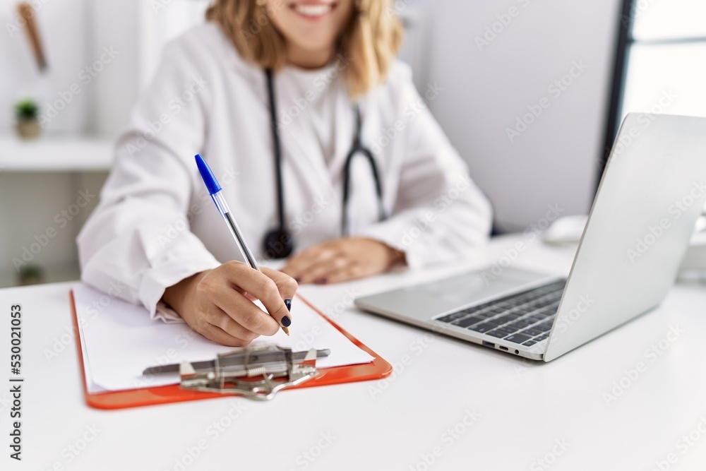 Fototapeta premium Young hispanic woman wearing doctor stethoscope working at clinic