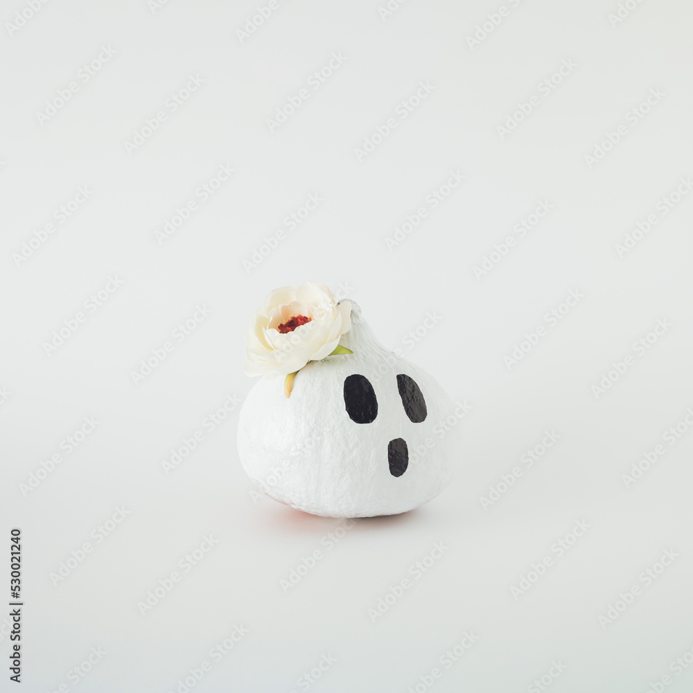 Happy Halloween. White pumpkin with drawn spooky face and white flower on white background. Happy Halloween. White pumpkin with drawn spooky face and white flower on white background.