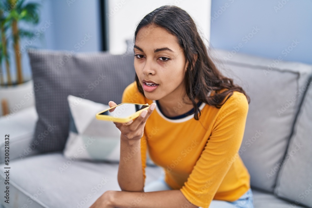 Young african american woman talking on the smartphone sitting on sofa at home Young african american woman talking on the smartphone sitting on sofa at home