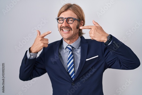 Caucasian man with mustache wearing business clothes smiling cheerful showing and pointing with fingers teeth and mouth. dental health concept.