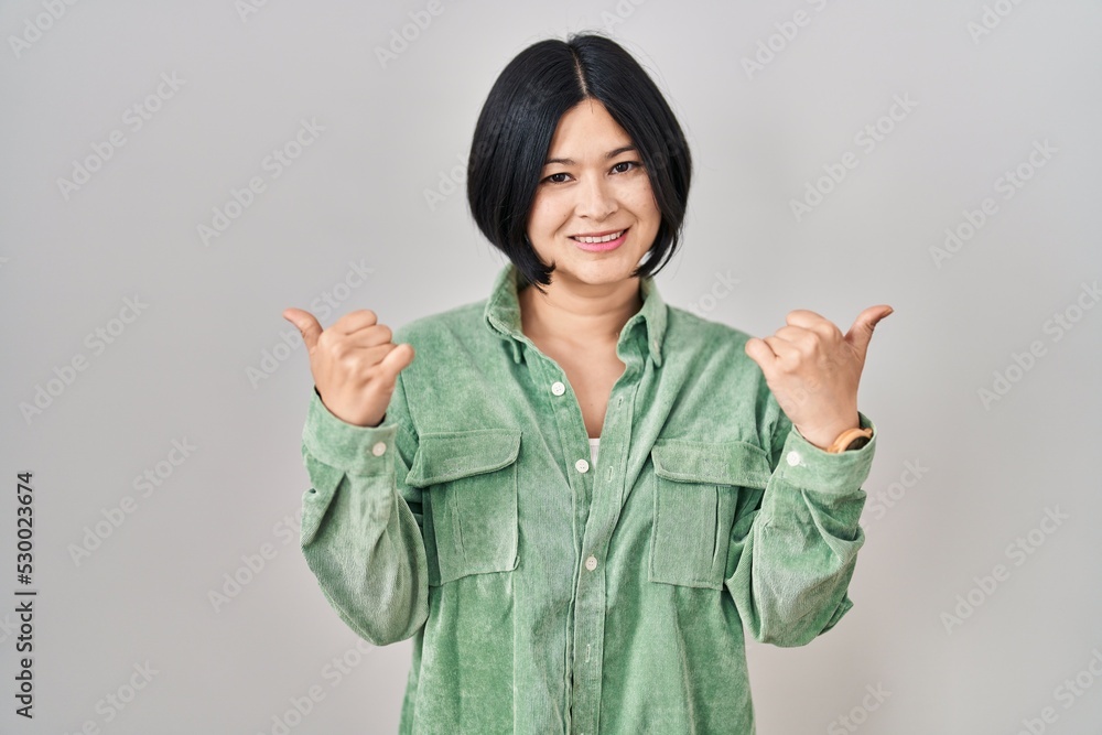 Young asian woman standing over white background success sign doing positive gesture with hand, thumbs up smiling and happy. cheerful expression and winner gesture. Young asian woman standing over white background success sign doing positive gesture with hand, thumbs up smiling and happy. cheerful expression and winner gesture.