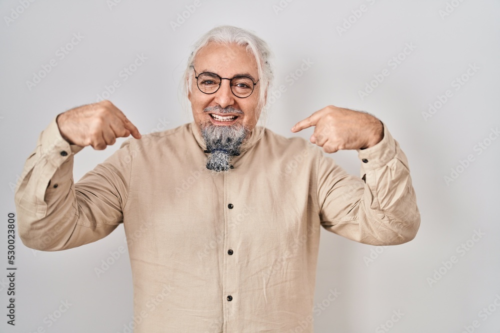 Middle age man with grey hair standing over isolated background looking confident with smile on face, pointing oneself with fingers proud and happy.