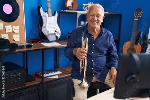 Canvas Print Senior grey-haired man musician holding trumpet at music studio