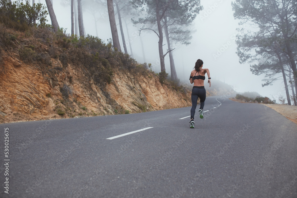 Obraz premium Female runner sprinting along a country road