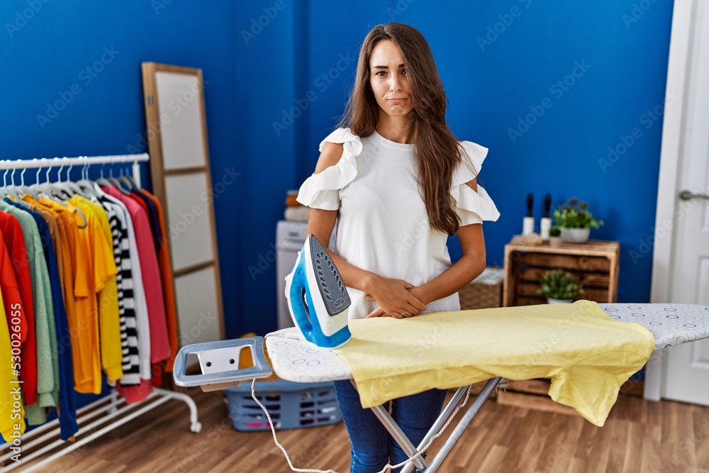 Young hispanic woman ironing clothes at laundry room depressed and worry for distress, crying angry and afraid. sad expression. Young hispanic woman ironing clothes at laundry room depressed and worry for distress, crying angry and afraid. sad expression.