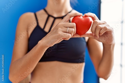 Young hispanic woman holding heart at sport center