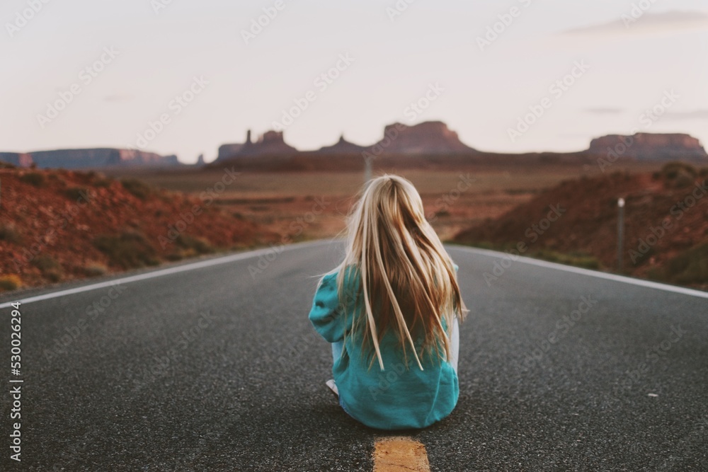 Rear View Of Woman Sitting On Road - obrazy, fototapety, plakaty 