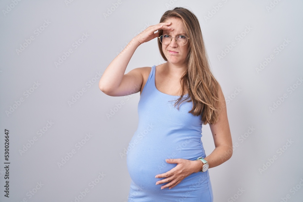 Young pregnant woman standing over white background worried and stressed about a problem with hand on forehead, nervous and anxious for crisis Young pregnant woman standing over white background worried and stressed about a problem with hand on forehead, nervous and anxious for crisis