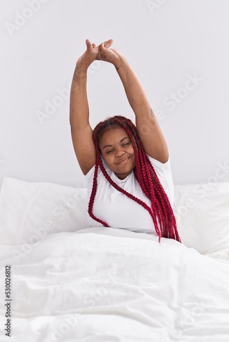 African american woman waking up stretching arms at bedroom photo