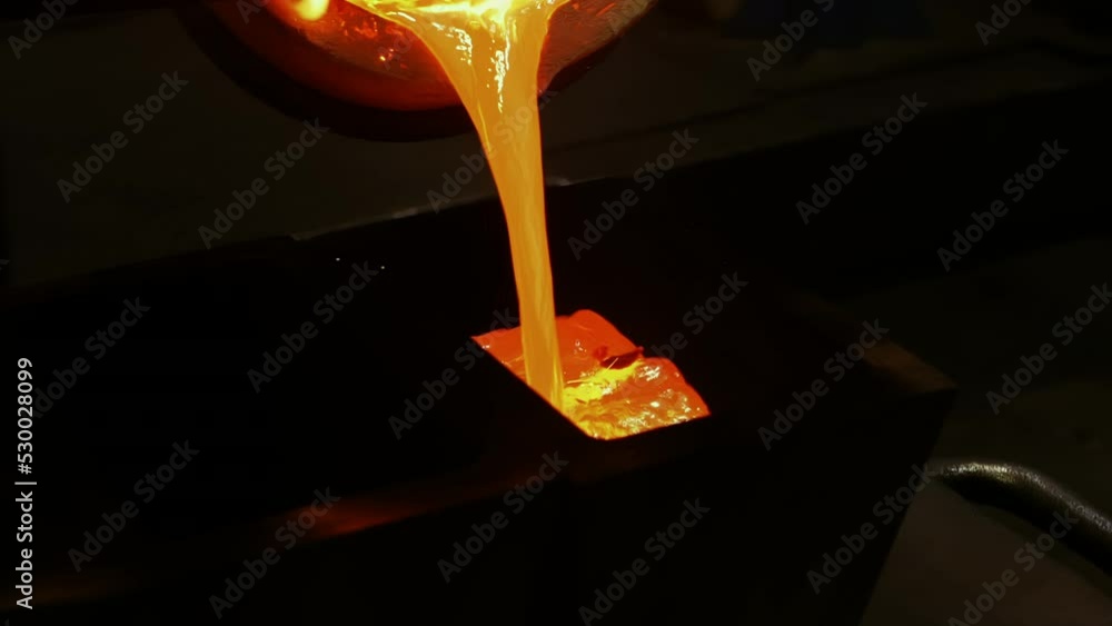 Molten metal is flowing out of industrial furnace at metalworking plant