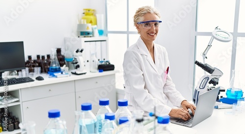 Middle age blonde woman wearing scientist uniform working at laboratory