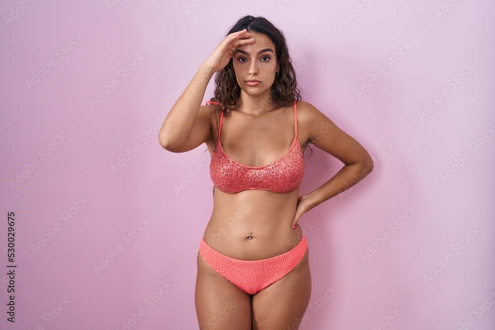 Obraz premium Young hispanic woman wearing lingerie over pink background worried and stressed about a problem with hand on forehead, nervous and anxious for crisis