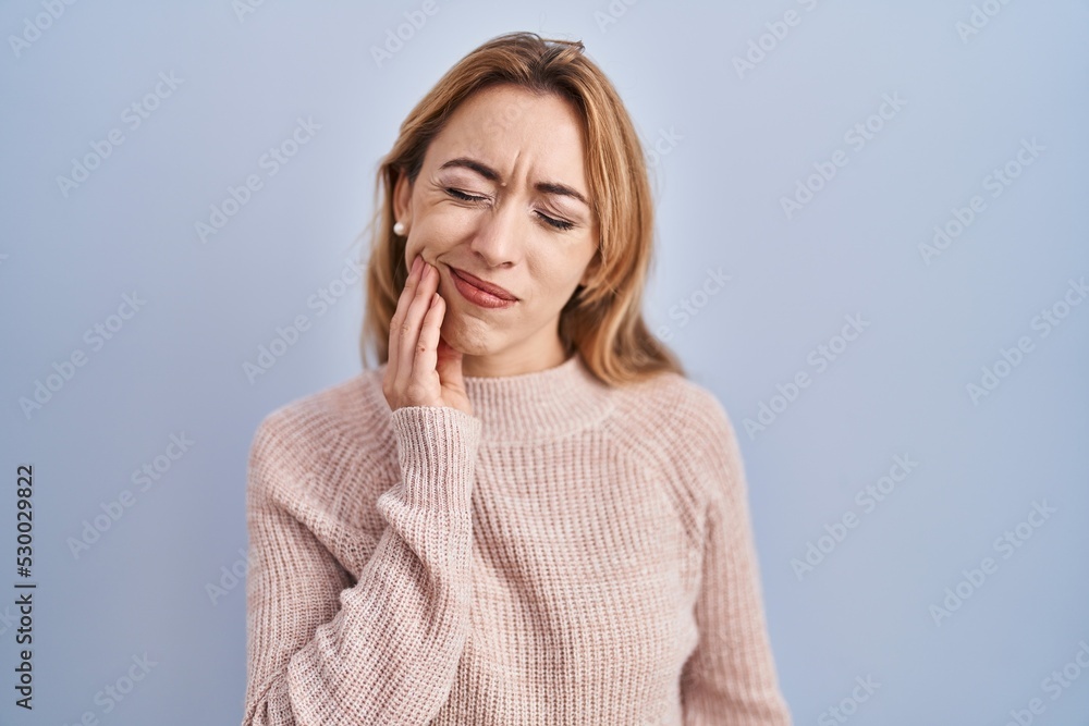 Hispanic woman standing over blue background touching mouth with hand with painful expression because of toothache or dental illness on teeth. dentist Hispanic woman standing over blue background touching mouth with hand with painful expression because of toothache or dental illness on teeth. dentist