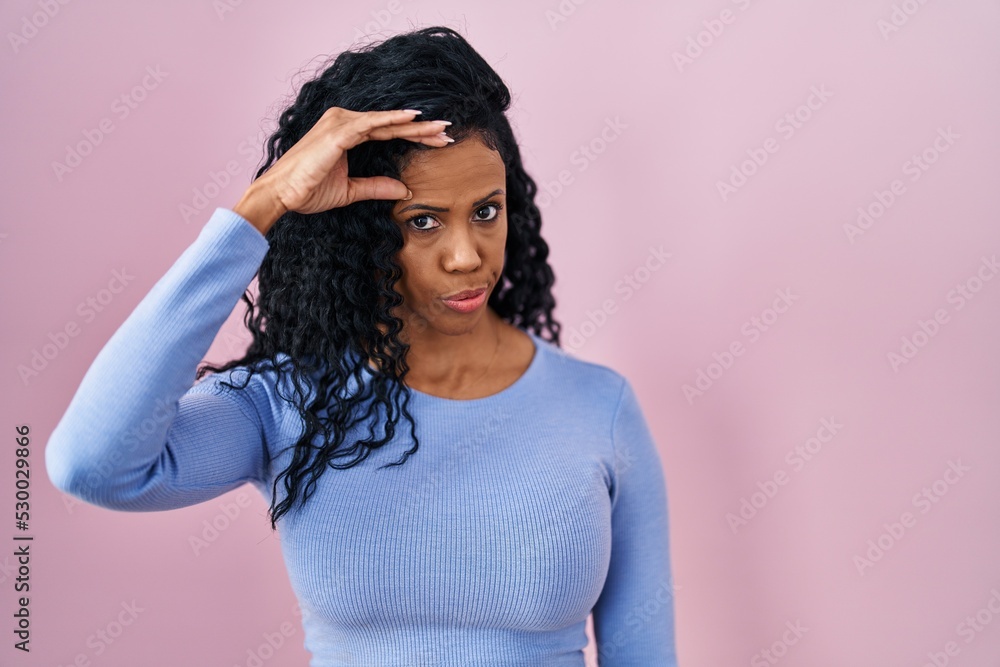 Middle age hispanic woman standing over pink background worried and stressed about a problem with hand on forehead, nervous and anxious for crisis Middle age hispanic woman standing over pink background worried and stressed about a problem with hand on forehead, nervous and anxious for crisis