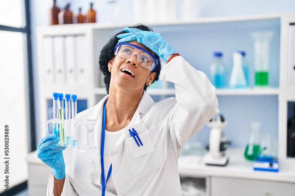 Middle age hispanic woman working at scientist laboratory stressed and frustrated with hand on head, surprised and angry face Middle age hispanic woman working at scientist laboratory stressed and frustrated with hand on head, surprised and angry face