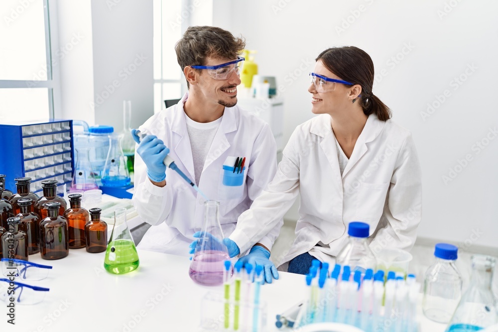 Man and woman partners wearing scientist uniform holding test tube and pipette at laboratory Man and woman partners wearing scientist uniform holding test tube and pipette at laboratory