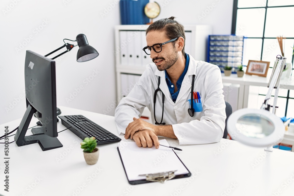 Handsome hispanic man working as doctor speaking to a patient at hospital clinic