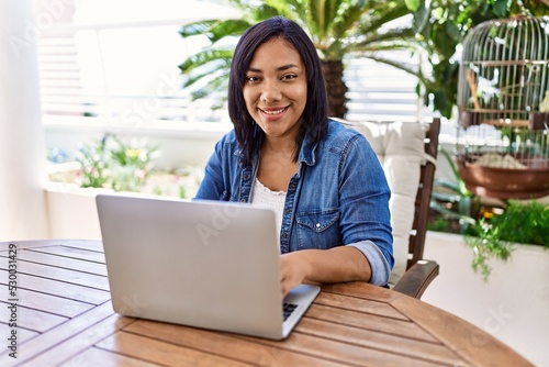 Hispanic brunette woman using laptop at the terrace