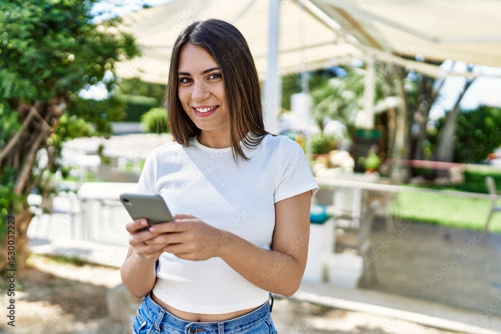 Young beautiful woman smiling happy outdoors on a sunny day using smartphone Young beautiful woman smiling happy outdoors on a sunny day using smartphone
