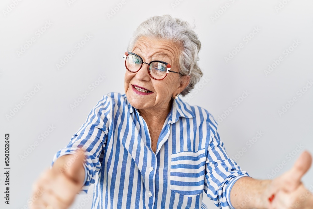 Senior woman with grey hair standing over white background approving doing positive gesture with hand, thumbs up smiling and happy for success. winner gesture. Senior woman with grey hair standing over white background approving doing positive gesture with hand, thumbs up smiling and happy for success. winner gesture.