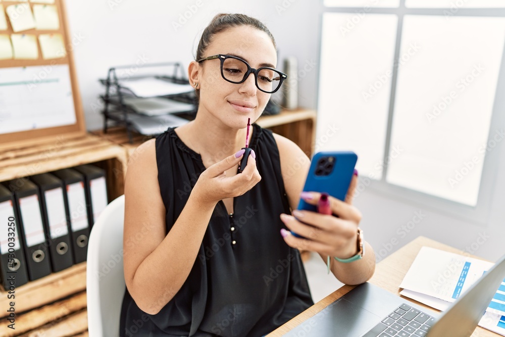 Young hispanic businesswoman smiling happy painting lips at the office. Young hispanic businesswoman smiling happy painting lips at the office.