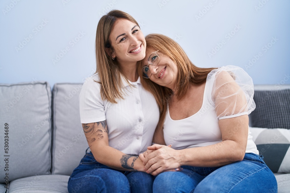 Mother and daughter hugging each other sitting on sofa at home Mother and daughter hugging each other sitting on sofa at home