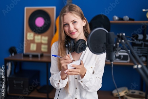 Young caucasian woman artist smiling confident composing song at music studio