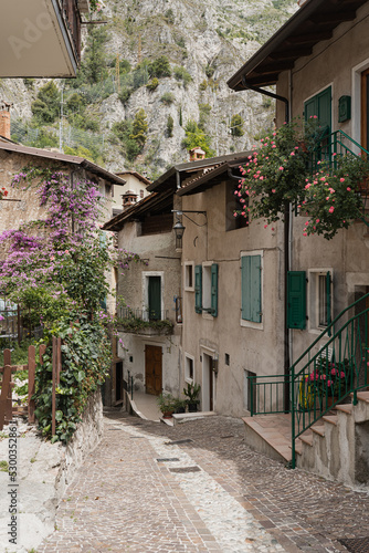 Old historic Italian architecture. Traditional European village rustic buildings. Flowers  wooden windows  shutters and pastel walls with sunlight shadows. Aesthetic summer vacation travel background