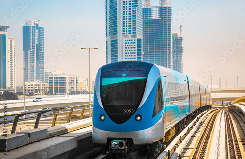 Dubai, UAE. Tube, metro railway track view with City buildings and approaching train