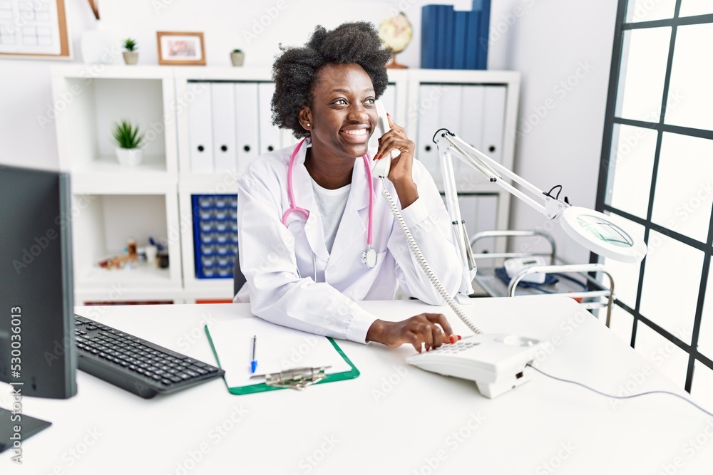 Young african american woman wearing doctor uniform talking on the telephone at clinic