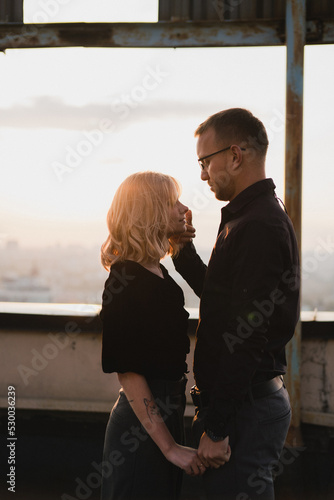 Romantic, young and happy caucasian couple in stylish clothes on the rooftop enjoying view and time together. Art portrait of beautiful woman and man. Love, relationships, romance, happiness concept.