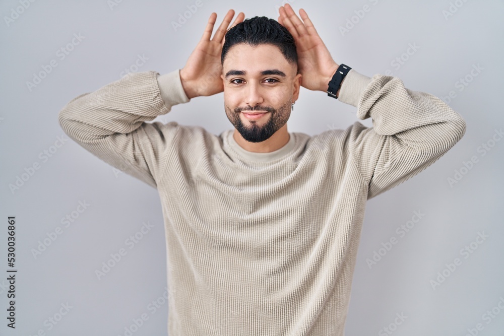 Young handsome man standing over isolated background doing bunny ears gesture with hands palms looking cynical and skeptical. easter rabbit concept. Young handsome man standing over isolated background doing bunny ears gesture with hands palms looking cynical and skeptical. easter rabbit concept.