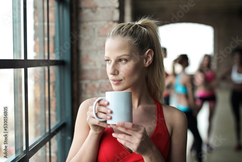 portrait of young woman in a gym while drinking from a cup