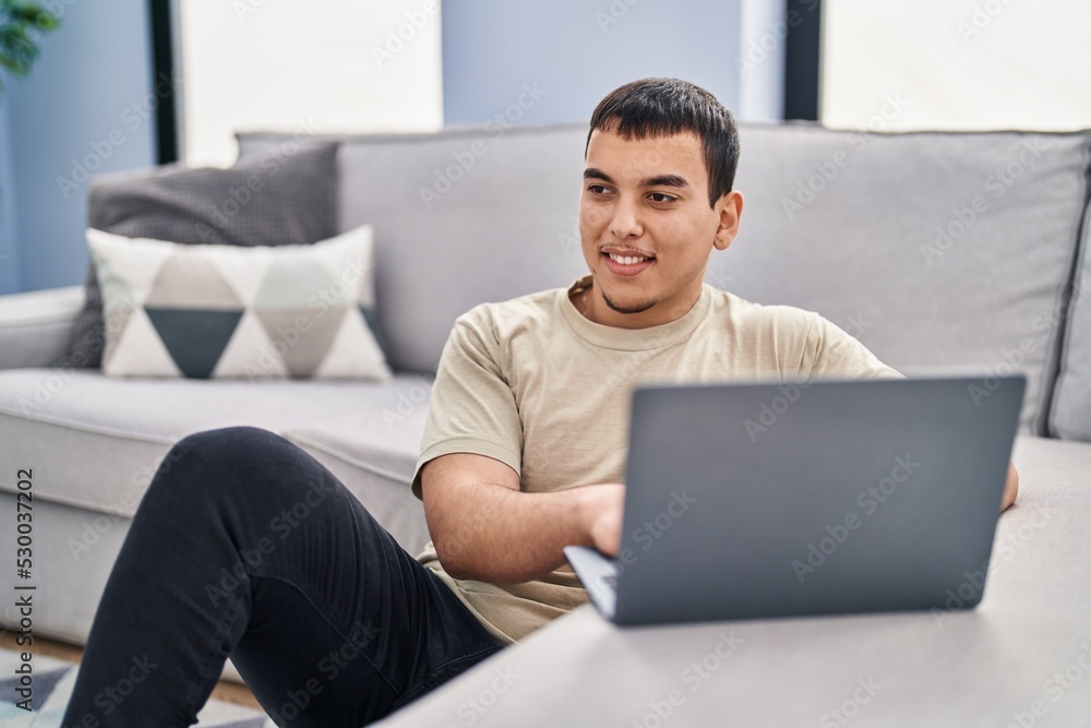Young man using laptop sitting on floor at home Young man using laptop sitting on floor at home
