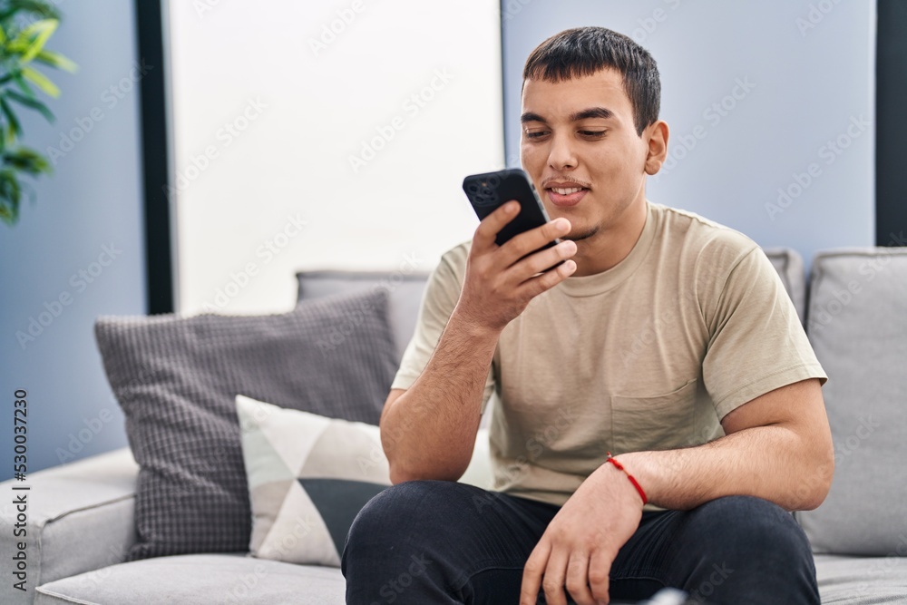 Young man using smartphone sitting on sofa at home Young man using smartphone sitting on sofa at home