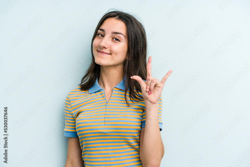 Young caucasian woman isolated on blue background showing a horns gesture as a revolution concept. Young caucasian woman isolated on blue background showing a horns gesture as a revolution concept.