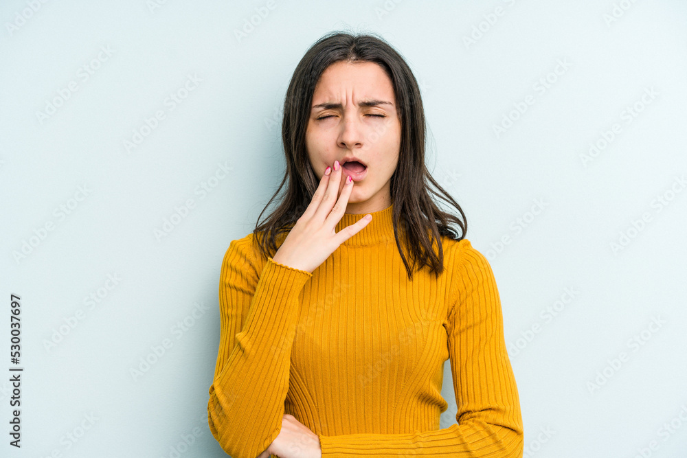 Young caucasian woman isolated on blue background yawning showing a tired gesture covering mouth with hand. Young caucasian woman isolated on blue background yawning showing a tired gesture covering mouth with hand.