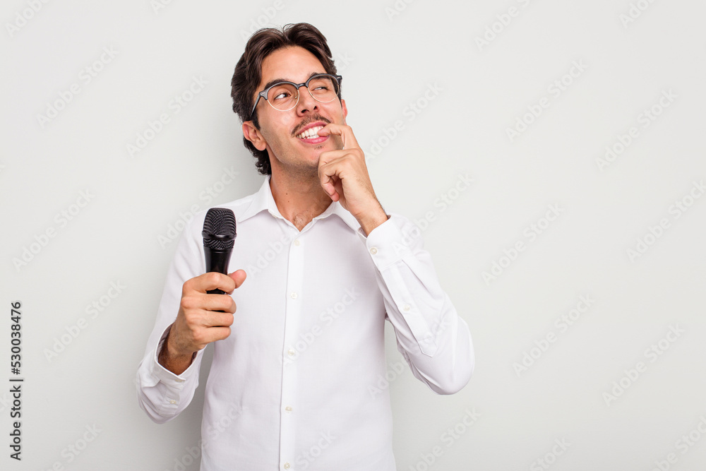 Young hispanic singer man isolated on white background relaxed thinking about something looking at a copy space. Young hispanic singer man isolated on white background relaxed thinking about something looking at a copy space.