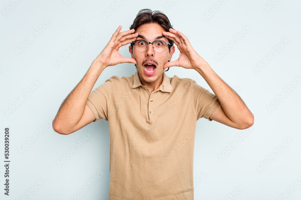 Young hispanic man isolated on blue background receiving a pleasant surprise, excited and raising hands. Young hispanic man isolated on blue background receiving a pleasant surprise, excited and raising hands.