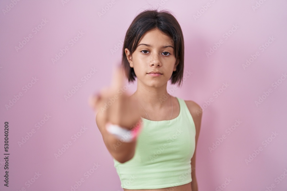 Young girl standing over pink background showing middle finger, impolite and rude fuck off expression Young girl standing over pink background showing middle finger, impolite and rude fuck off expression