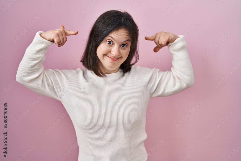 Woman with down syndrome standing over pink background smiling pointing to head with both hands finger, great idea or thought, good memory Woman with down syndrome standing over pink background smiling pointing to head with both hands finger, great idea or thought, good memory