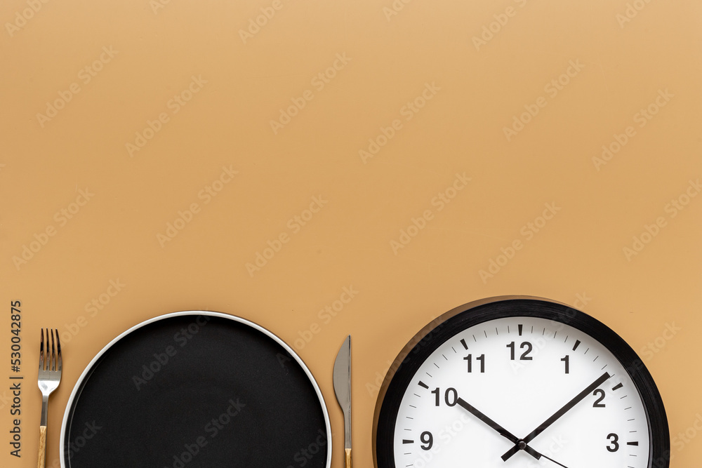 Round wall clock with empty plate. Diet or meal time concept Round wall clock with empty plate. Diet or meal time concept