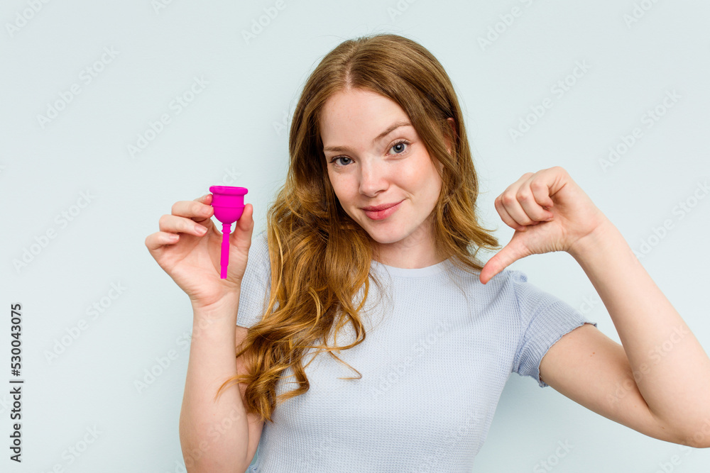 Young caucasian woman holding menstrual cup isolated on blue background feels proud and self confident, example to follow. Young caucasian woman holding menstrual cup isolated on blue background feels proud and self confident, example to follow.