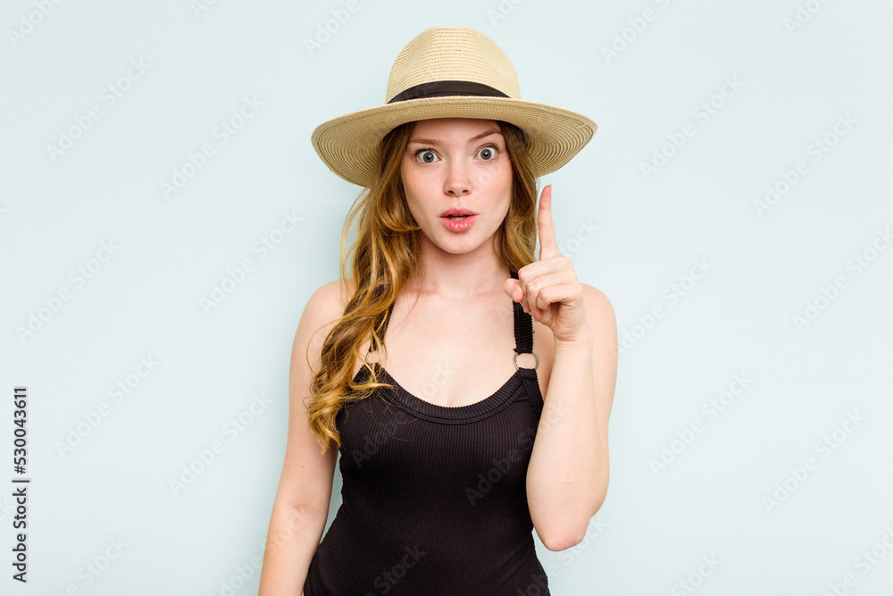 Young caucasian woman going to the beach isolated on blue background having some great idea, concept of creativity. Young caucasian woman going to the beach isolated on blue background having some great idea, concept of creativity.