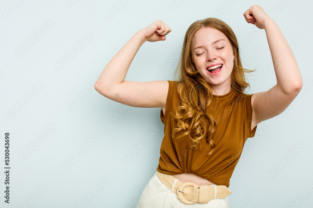 Young caucasian woman isolated on blue background raising fist after a victory, winner concept. Young caucasian woman isolated on blue background raising fist after a victory, winner concept.