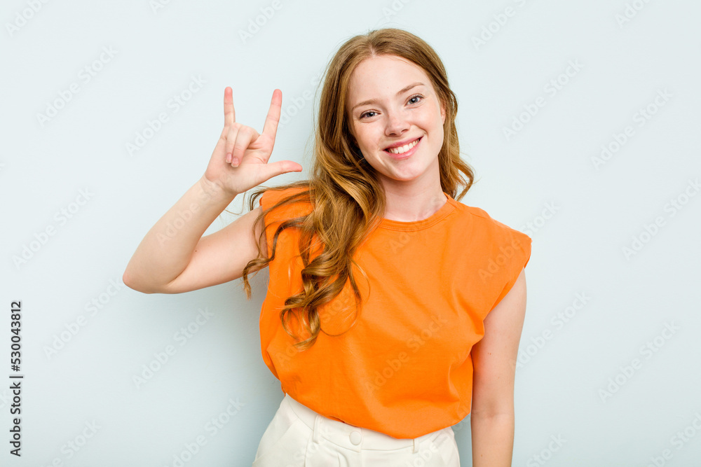 Fototapeta premium Young caucasian woman isolated on blue background showing a horns gesture as a revolution concept.