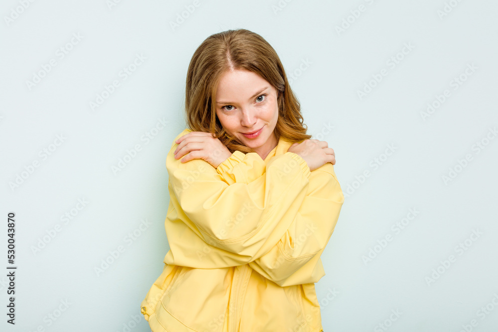 Young caucasian woman isolated on blue background hugs, smiling carefree and happy. Young caucasian woman isolated on blue background hugs, smiling carefree and happy.